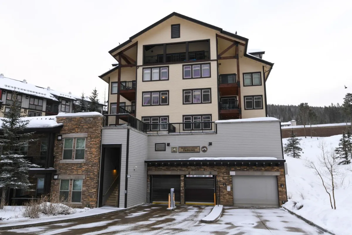 A picturesque winter scene featuring a multi-level lodge with stone facades and snow-covered surroundings. The building exudes warmth and hospitality, complemented by hints of festive decorations. The environment invites guests to enjoy skiing, snowboarding, or cozy gatherings inside after a day of adventure.