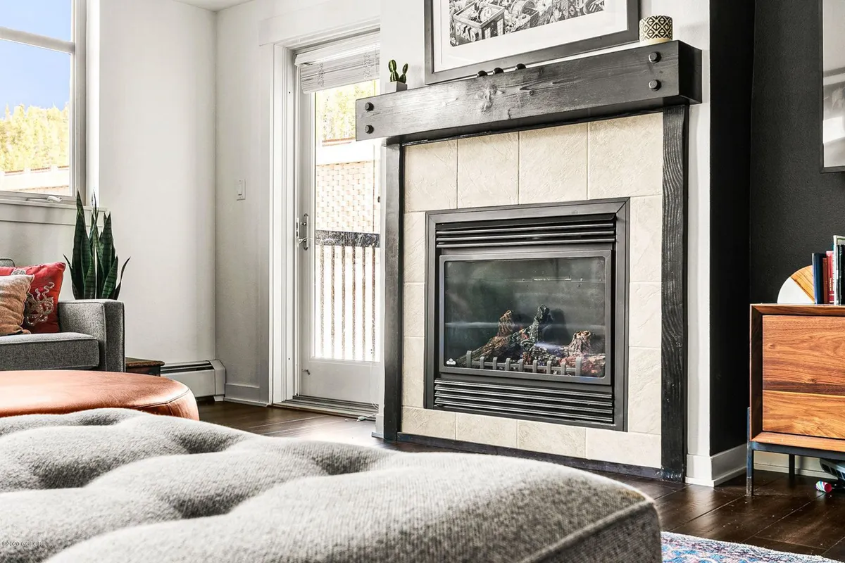 A warmly lit seating area anchored by a rustic gas fireplace, surrounded by a comfortable sofa and artwork. The intimate space invites guests to unwind with a book, hot cocoa, or good company after a day outdoors.